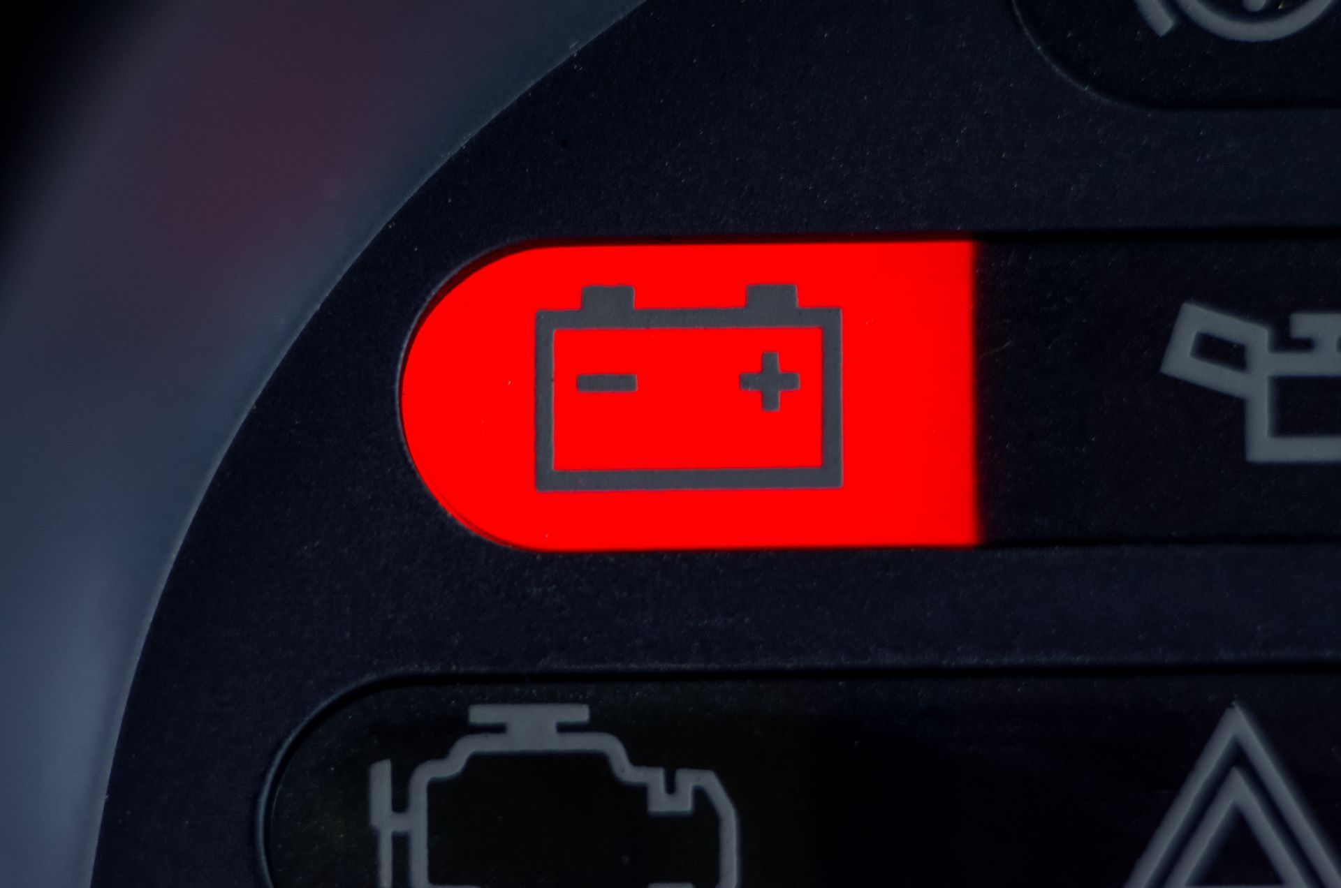 Red battery warning light illuminated on a car dashboard.